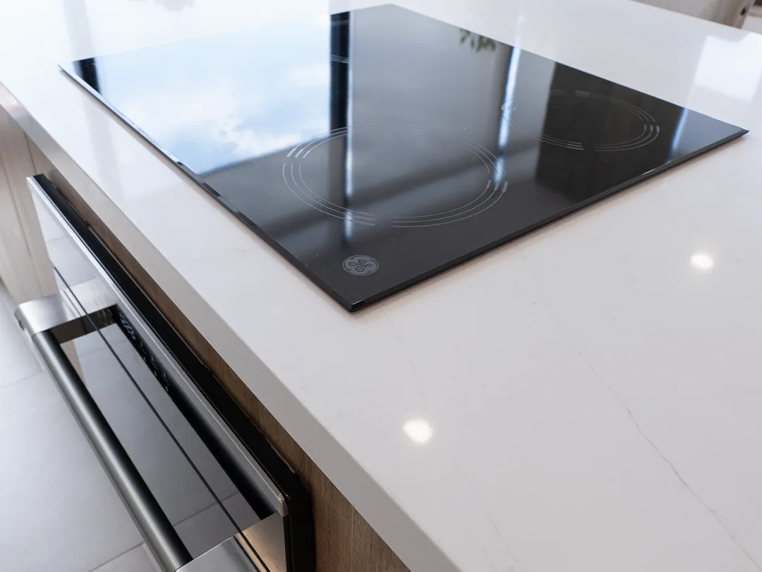 Detalle de parrilla de vitrocerámica GE Profile sobre cubierta de cuarzo blanco