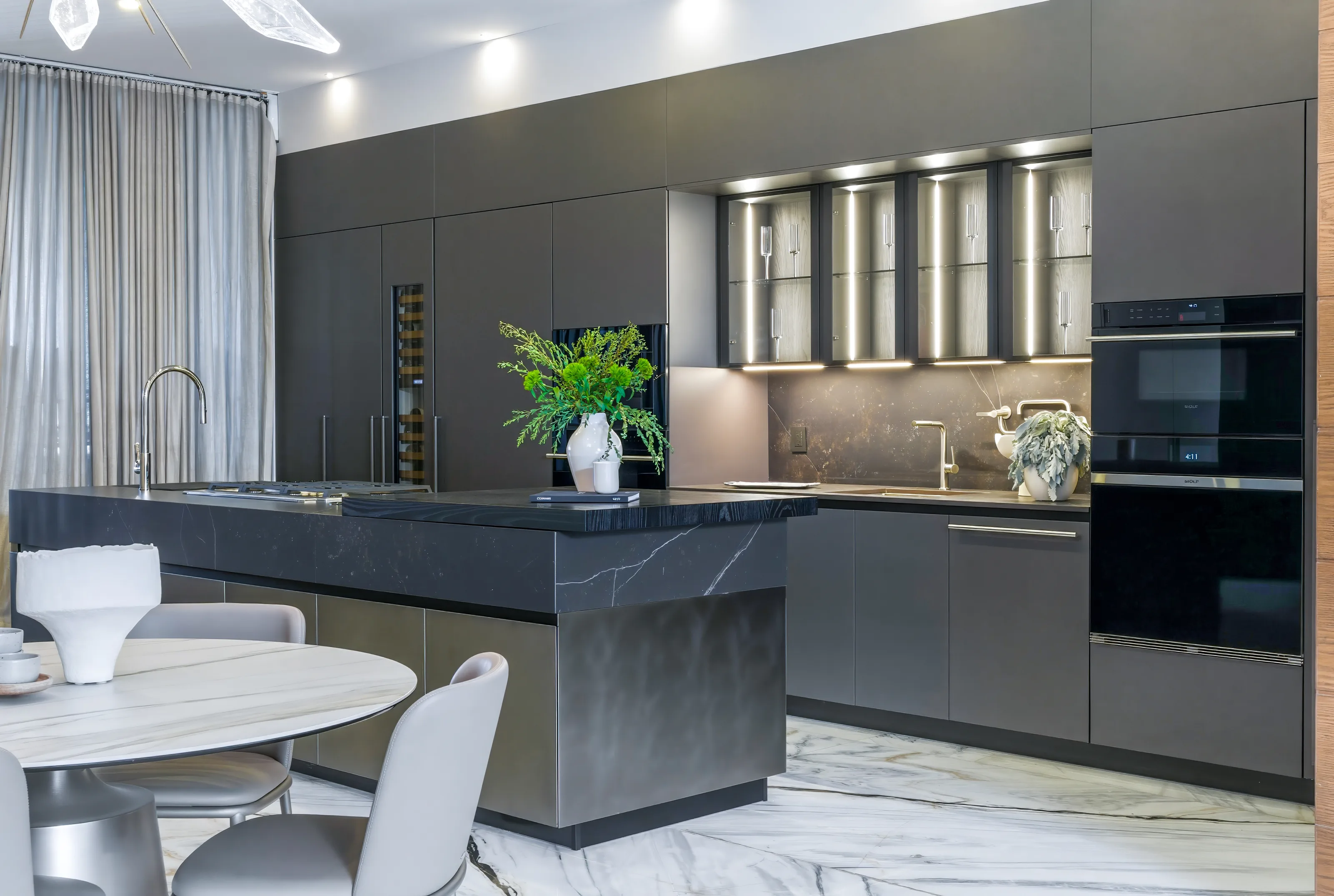 Cocina con isla de mármol negro y gabinetes iluminados en el espacio Homa Living