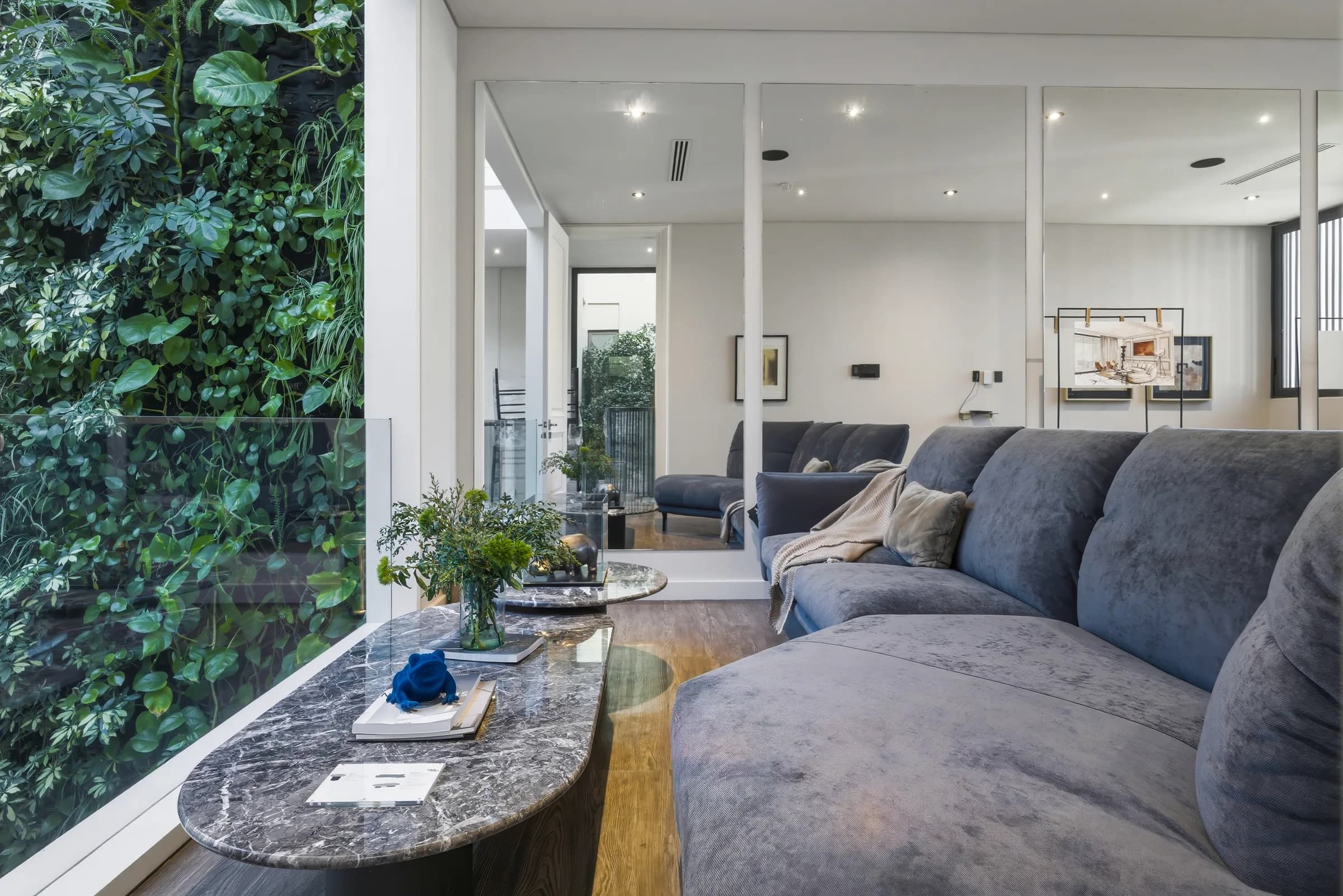 Sala del espacio Homa Living con muro verde y mesas de mármol