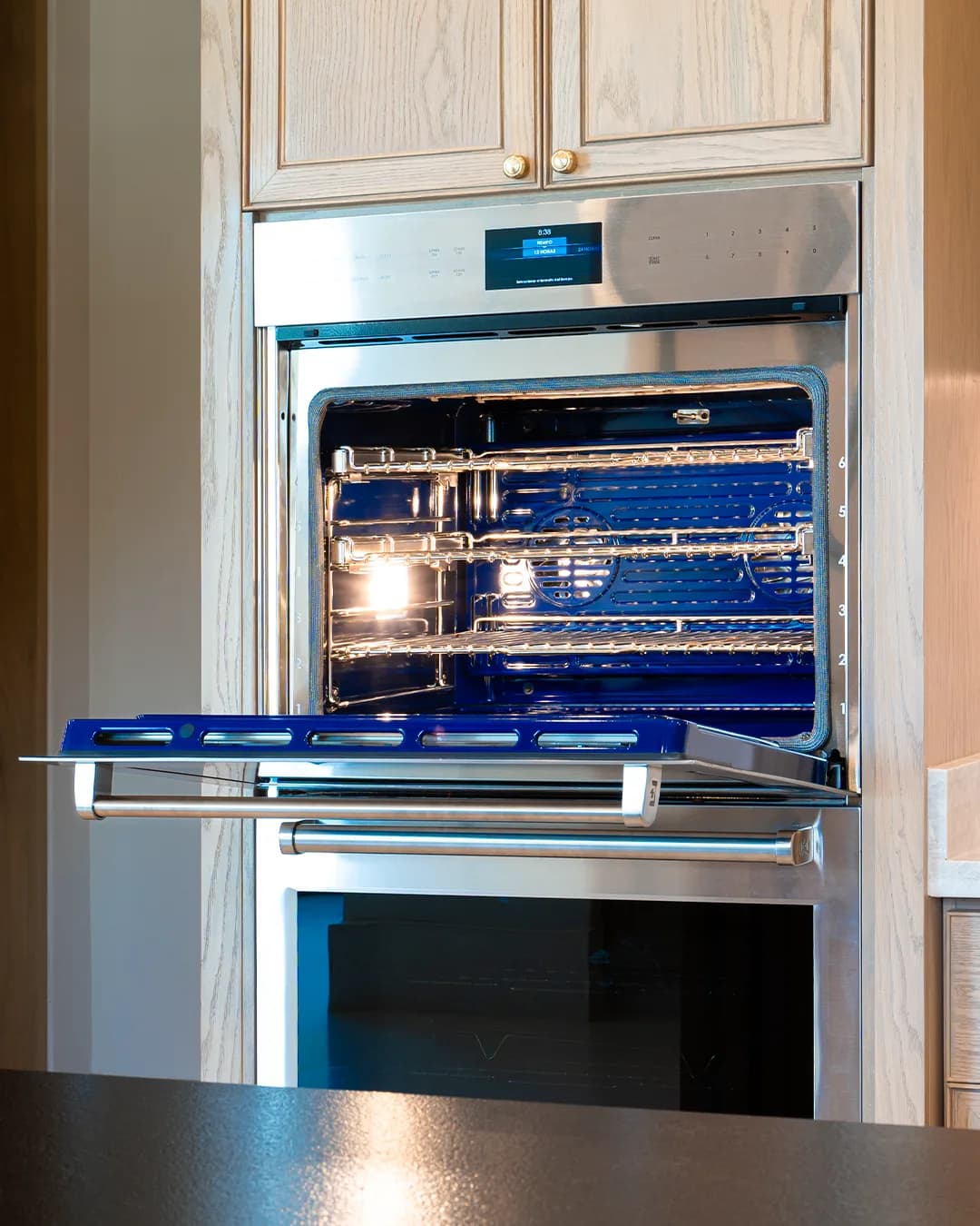 Horno Wolf abierto con interior azul cobalto en gabinetes de roble