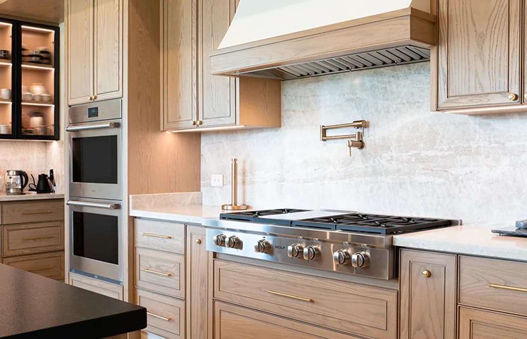 Rangetop Wolf instalado en cocina de roble claro con campana y doble horno
